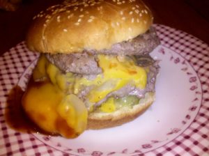 Two home ground beef patties, ketchup, mustard, bbq sauce, sharp cheddar cheese, onions, and Joe's homemade pickles, on a sesame seed bun